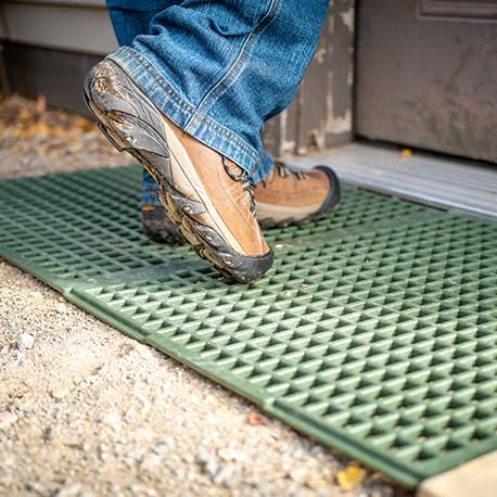 GEOBIN - Close-up of work boot stepping onto green GEORUNNER surface panel placed on gravel ground outside building